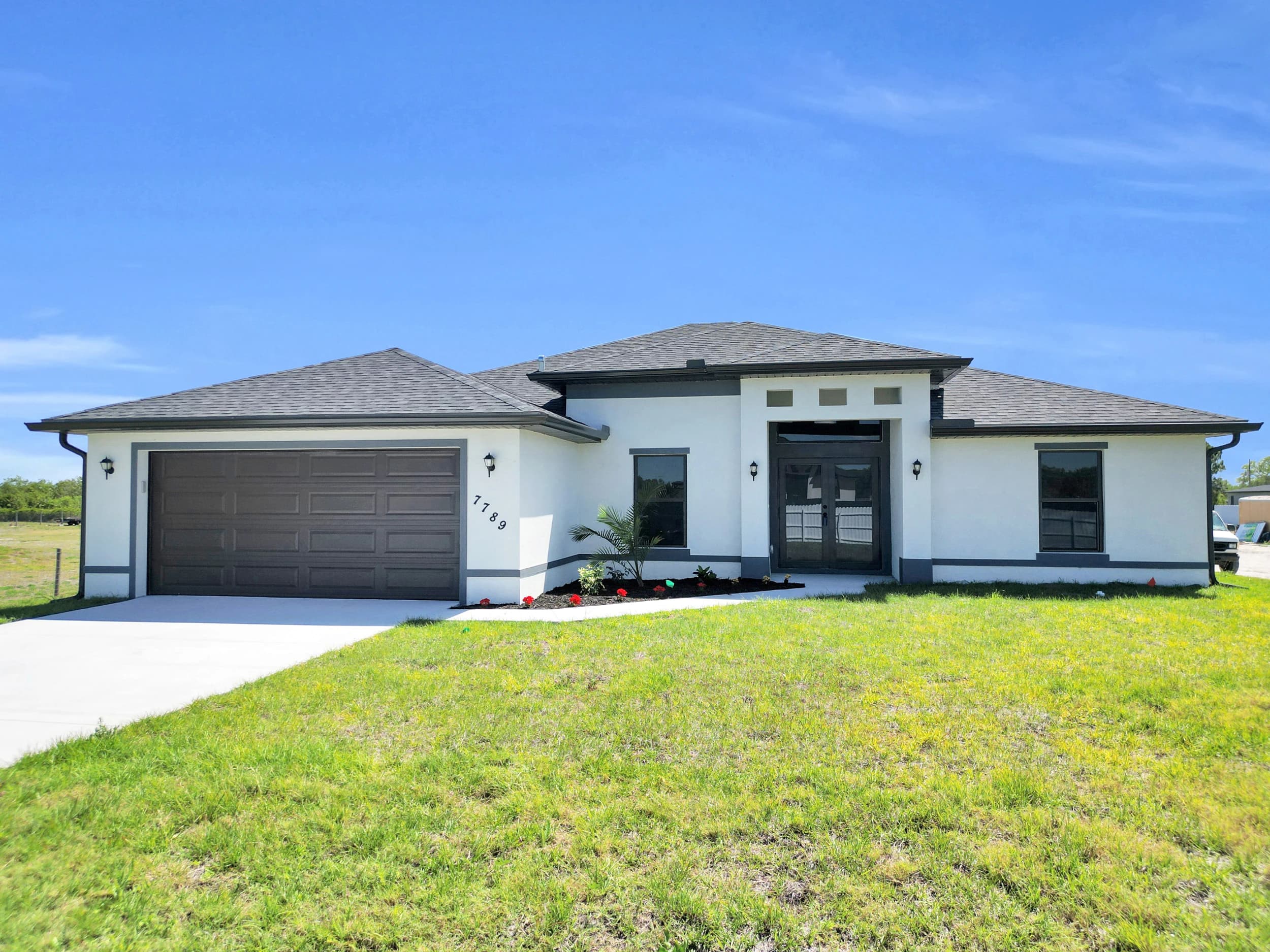A newly constructed modern home in Florida featuring a durable white metal roof installed by Labelle Dream Homes. Surrounded by lush greenery and palm trees, this home showcases expert roofing and construction craftsmanship.